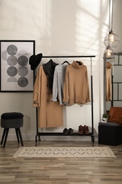 Stylish warm clothes on rack in dressing room interior