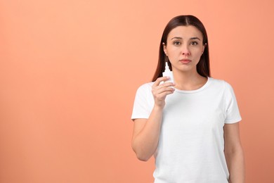 Photo of Woman with nasal spray on peach background, space for text
