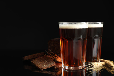 Photo of Delicious kvass, bread and spikes on black background