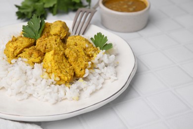 Photo of Delicious rice and chicken with curry sauce on white tiled table, closeup. Space for text