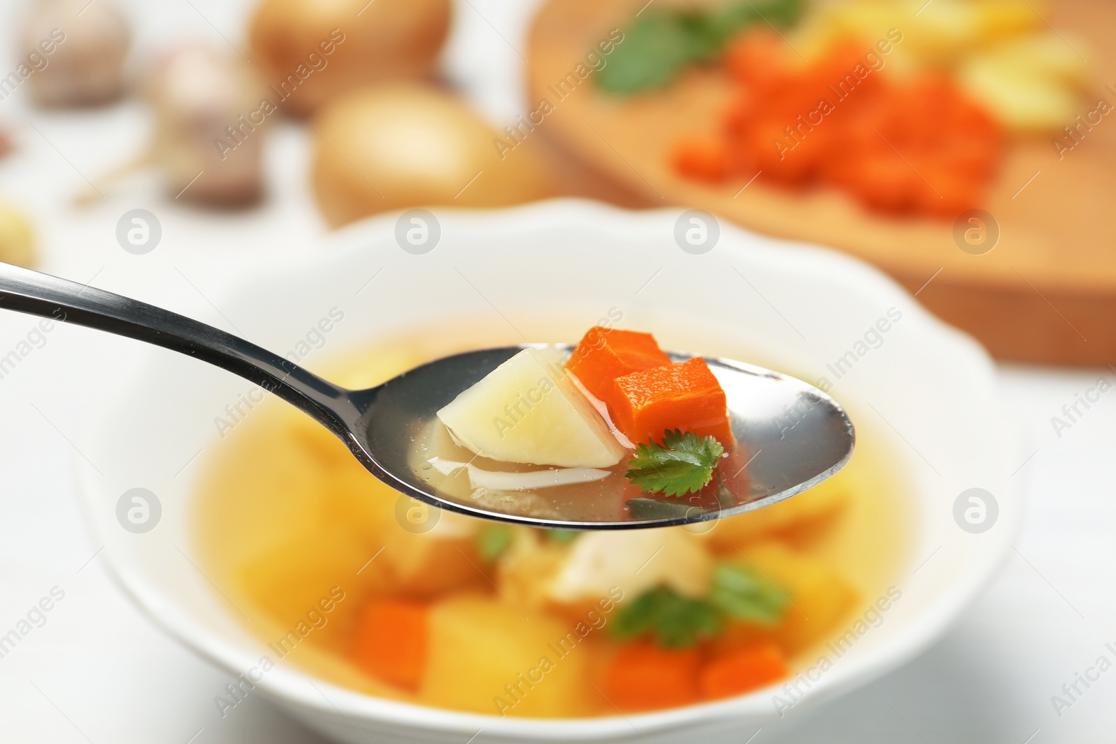 Photo of Spoon with fresh homemade chicken soup on blurred background, closeup