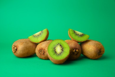 Photo of Heap of whole and cut fresh kiwis on green background