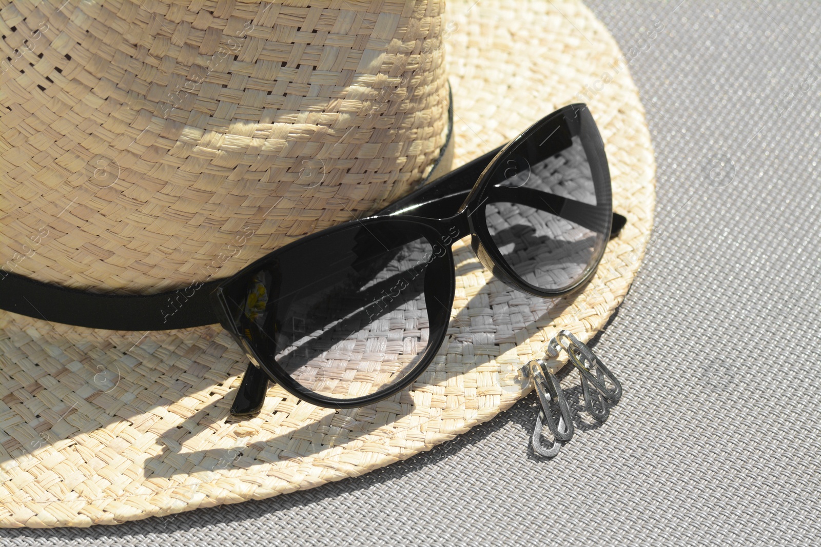 Photo of Stylish hat, sunglasses and jewelry on grey surface, closeup