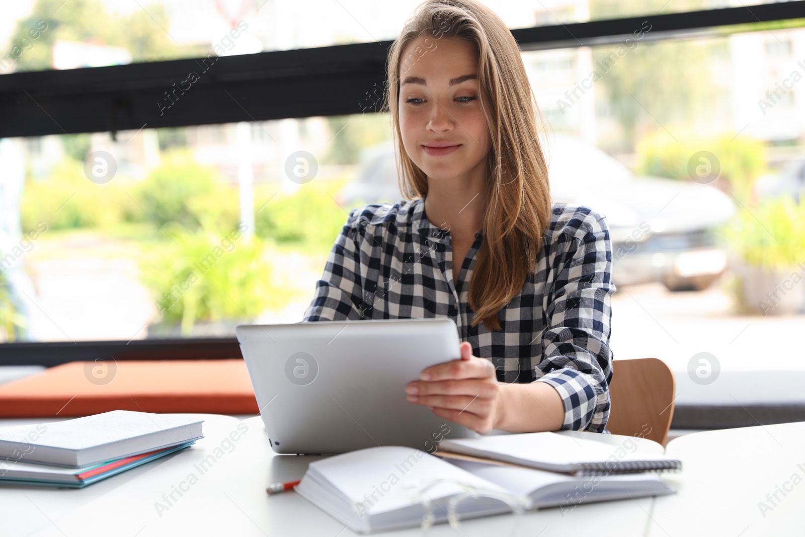 Photo of Young woman studying with tablet at table in library