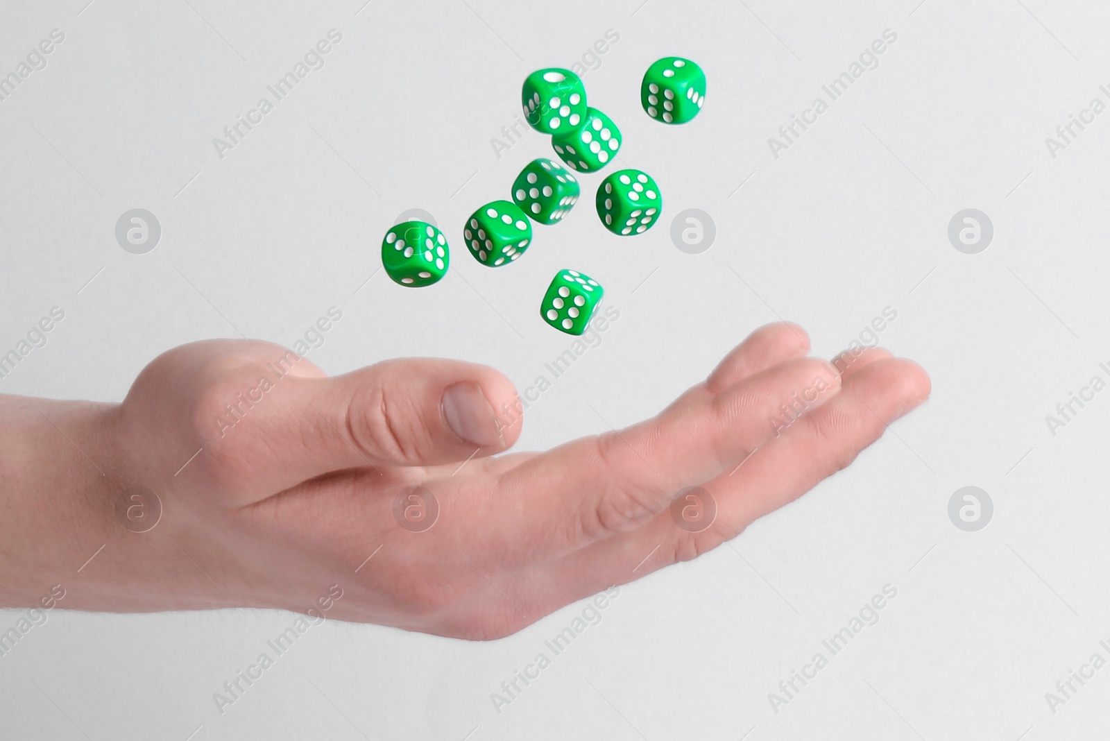 Photo of Man throwing game dices on white background, closeup