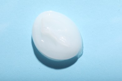 Photo of Drop of ointment on light blue background, top view