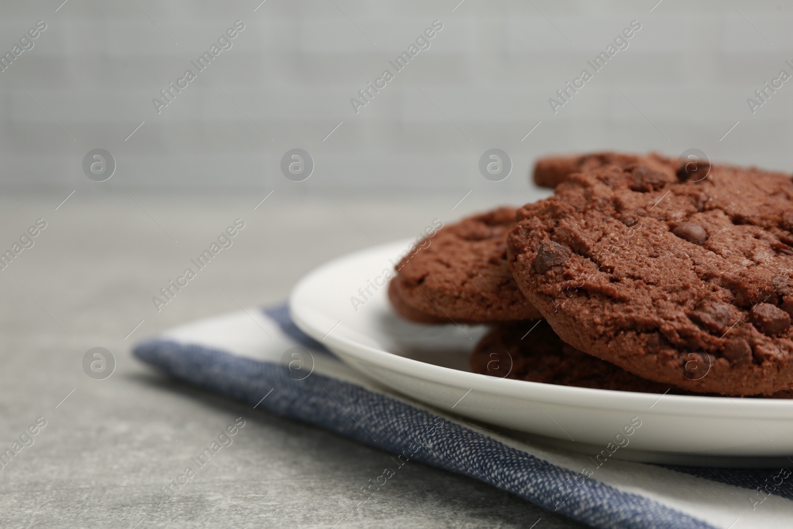 Photo of Delicious chocolate chip cookies on light grey table, closeup. Space for text