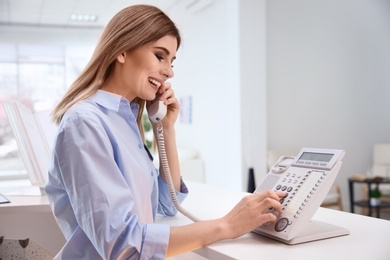 Photo of Female receptionist talking on phone at hotel check-in counter