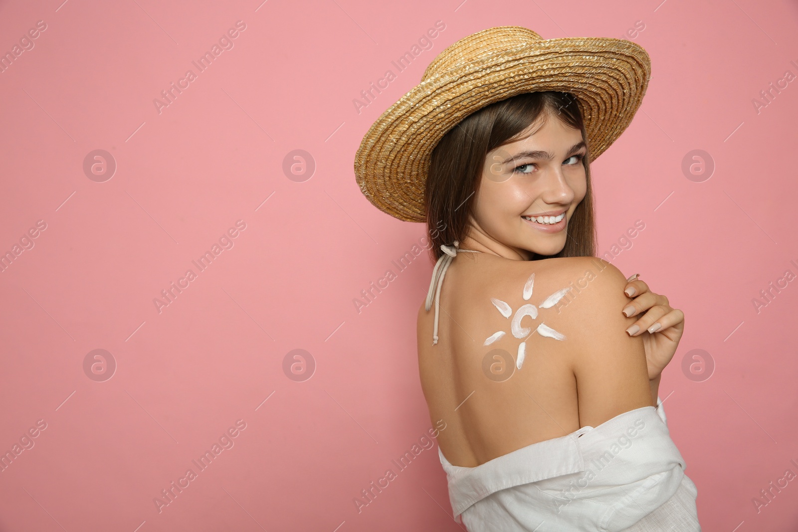 Photo of Teenage girl with sun protection cream on her back against pink background. Space for text