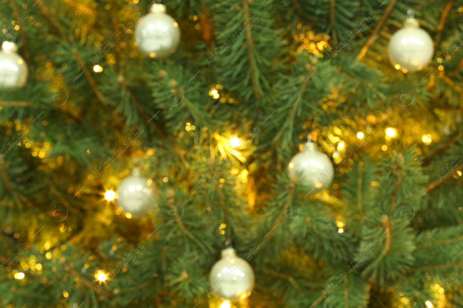 Photo of Blurred view of glowing fairy lights and beautiful baubles on Christmas tree