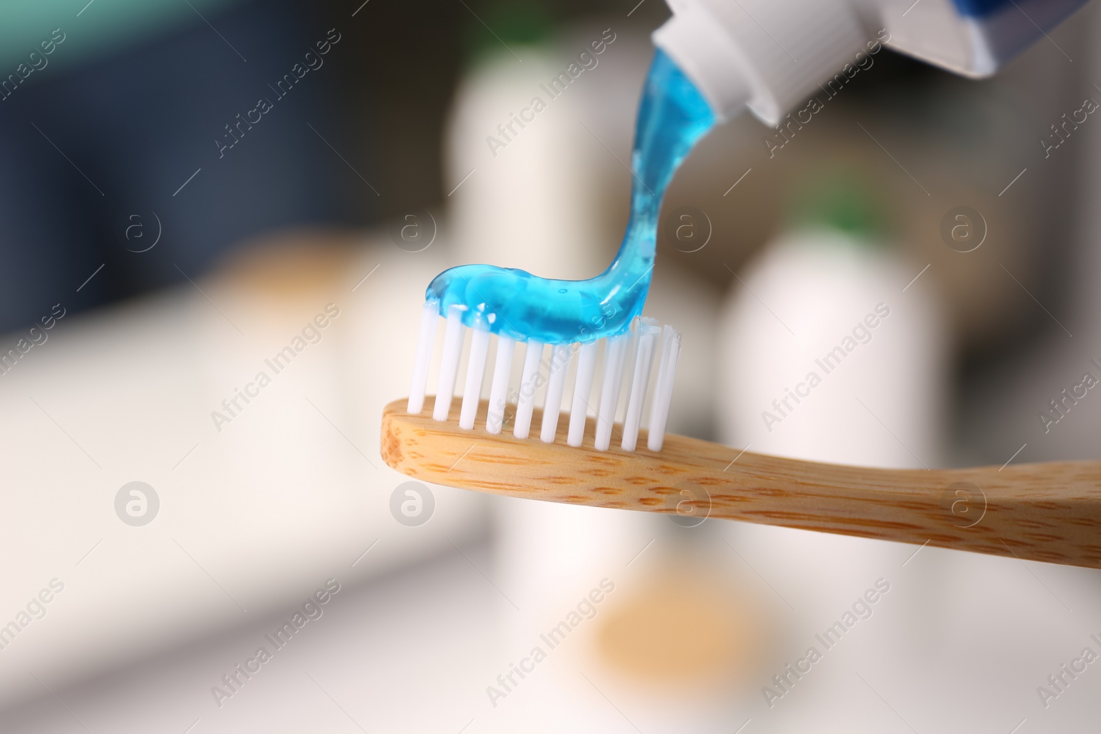 Photo of Applying toothpaste on brush against blurred background, closeup