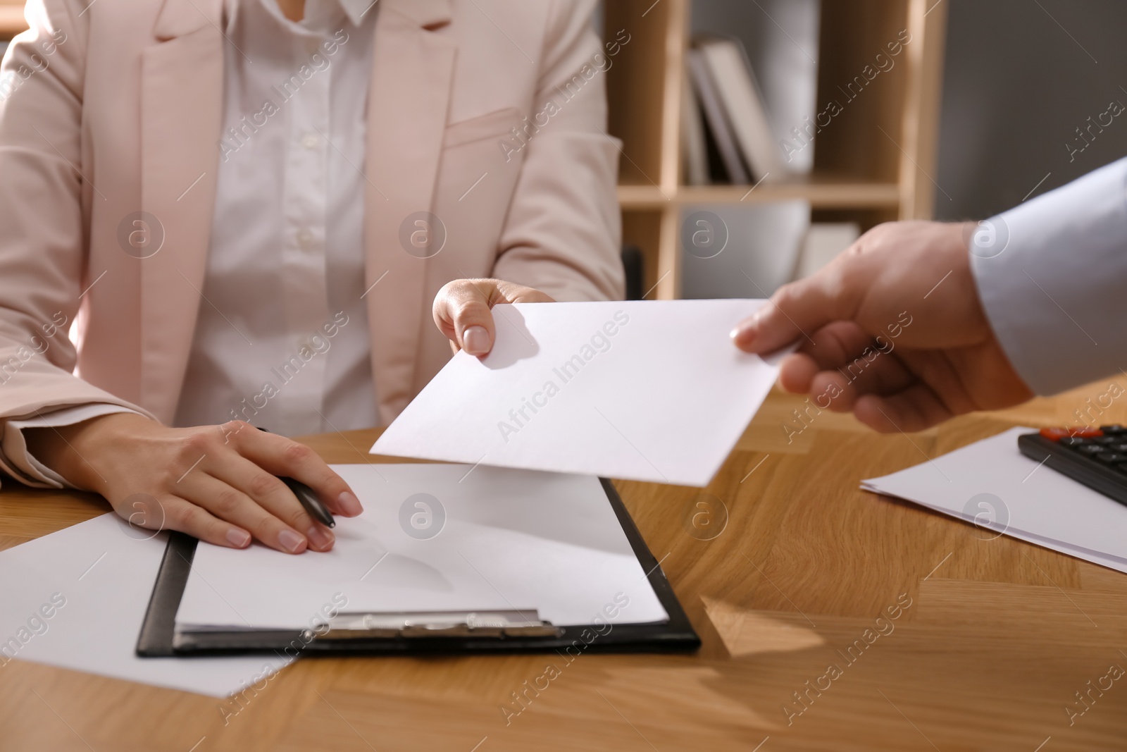 Photo of Employee giving resignation letter to boss in office, closeup