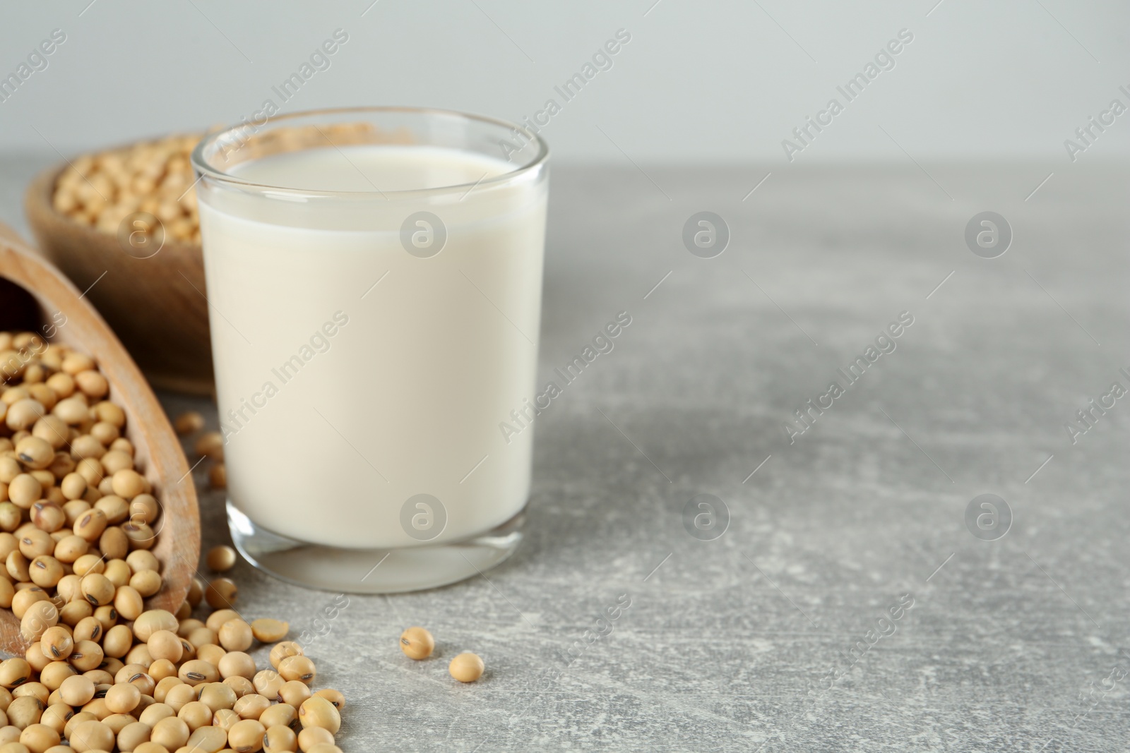 Photo of Glass with fresh soy milk and grains on grey table. Space for text