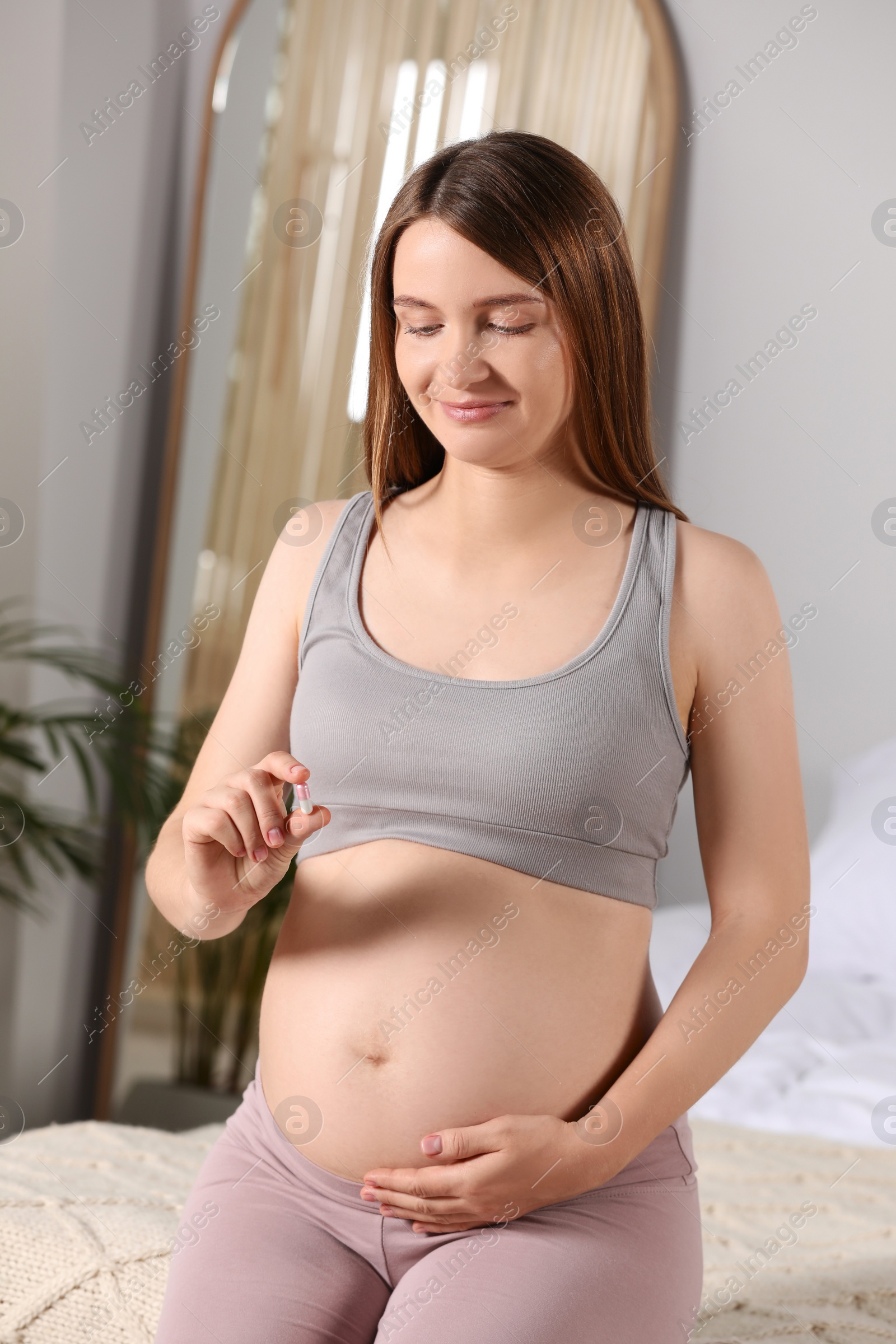 Photo of Beautiful pregnant woman taking pill at home