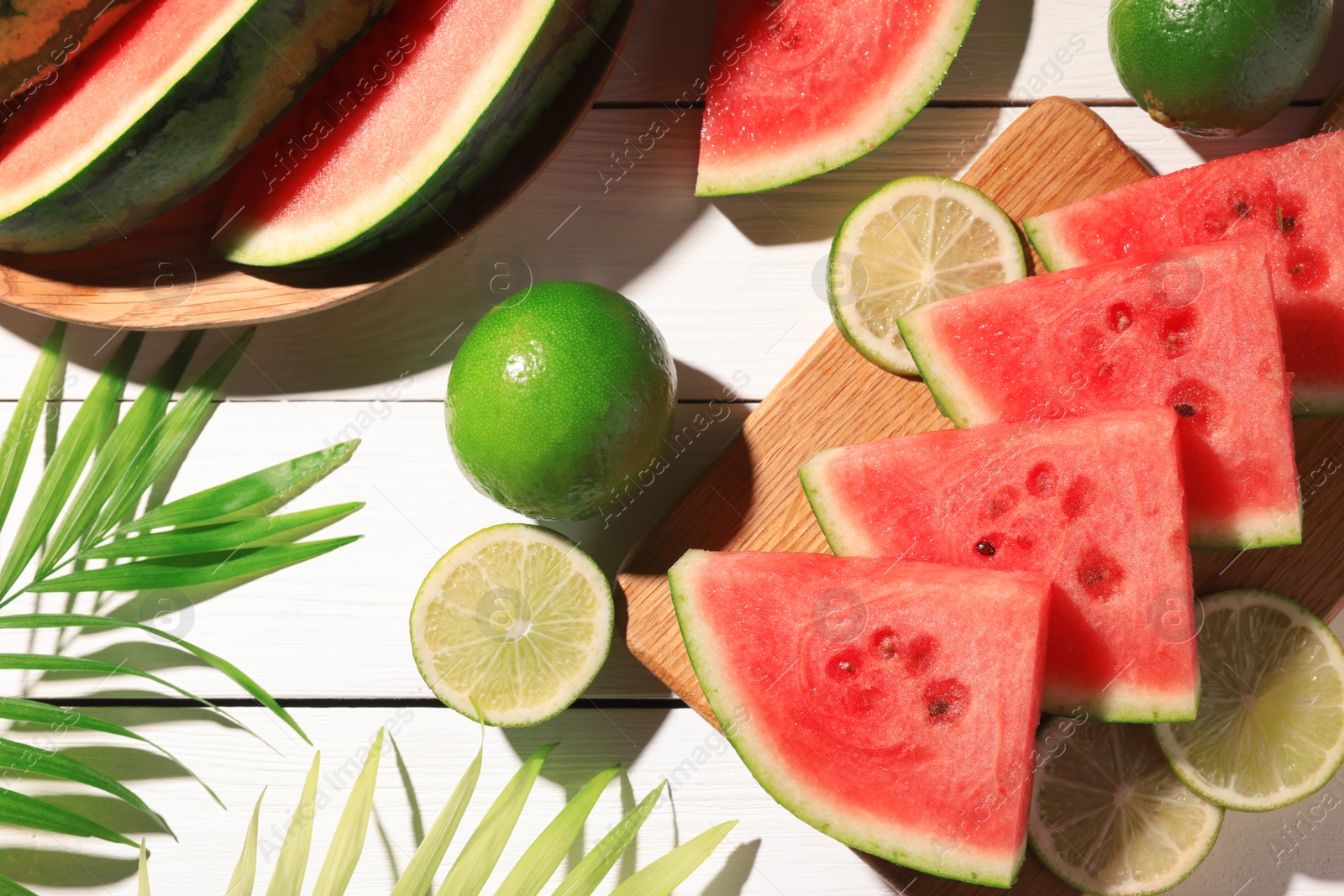 Photo of Tasty sliced watermelon and limes on white wooden table, flat lay