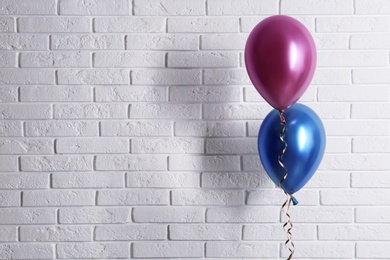 Photo of Bright colorful balloons near brick wall, space for text. Party time