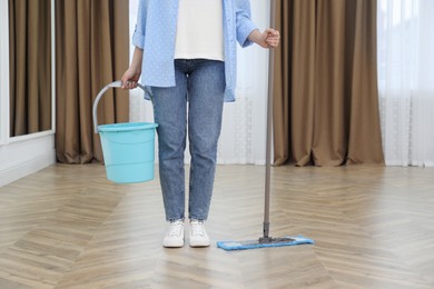 Photo of Woman with mop and bucket indoors, closeup. Cleaning service
