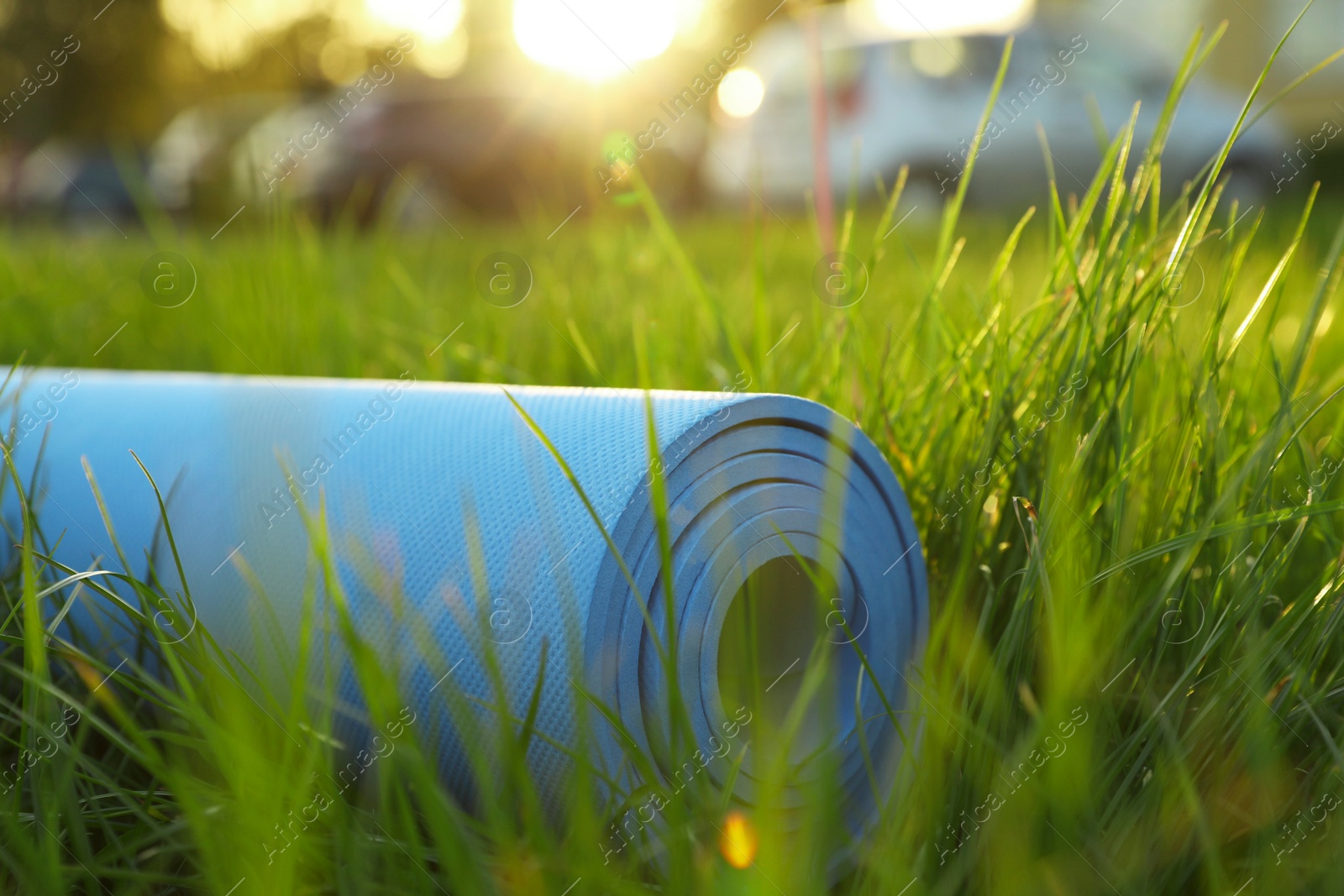 Photo of Bright karemat or fitness mat in fresh green grass outdoors, closeup