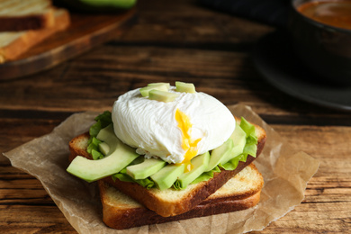 Photo of Delicious poached egg sandwich served on wooden table