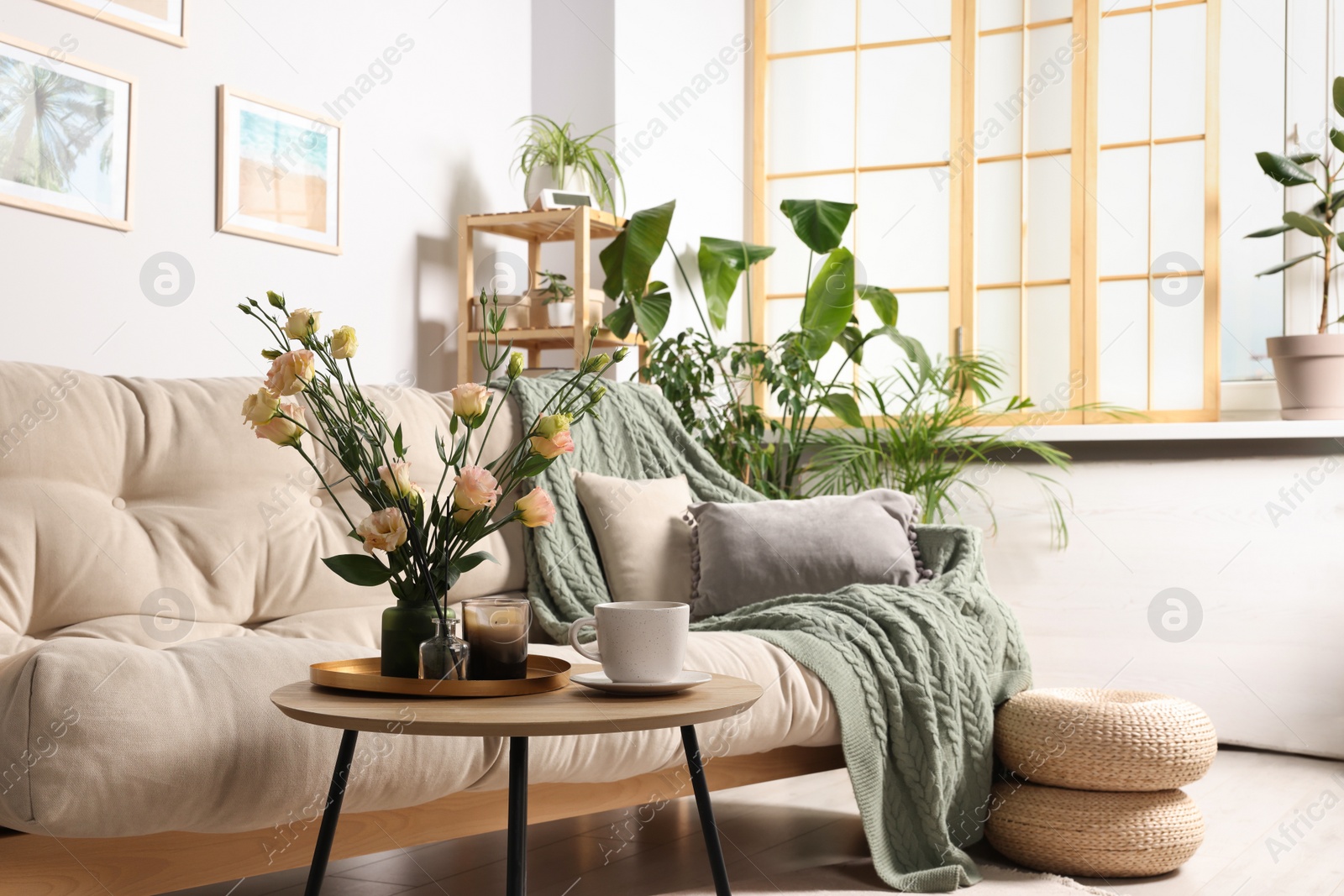 Photo of Stylish room interior with beautiful flowers and comfortable sofa