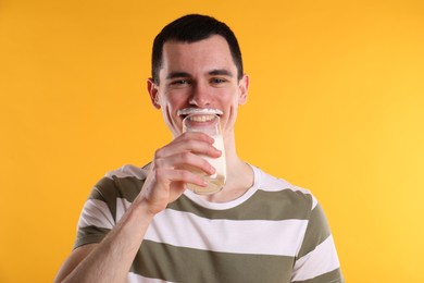 Milk mustache left after dairy product. Man drinking milk on orange background