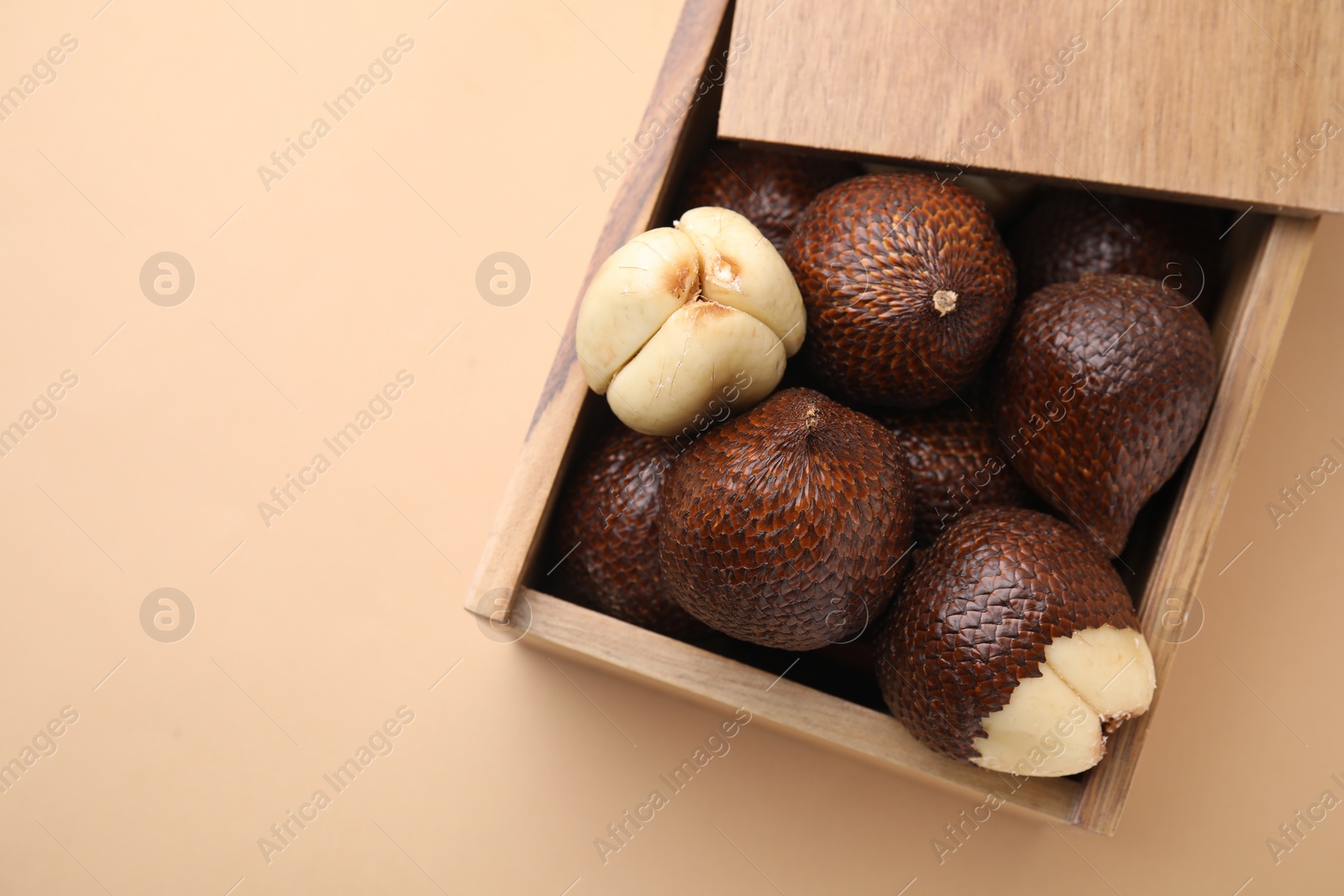 Photo of Wooden crate with fresh salak fruits on beige background, top view. Space for text