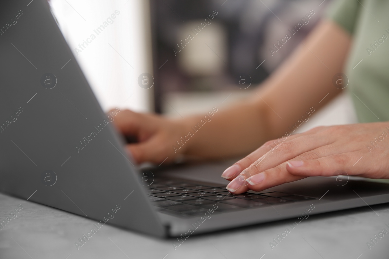 Photo of Woman working with modern laptop at light table, closeup