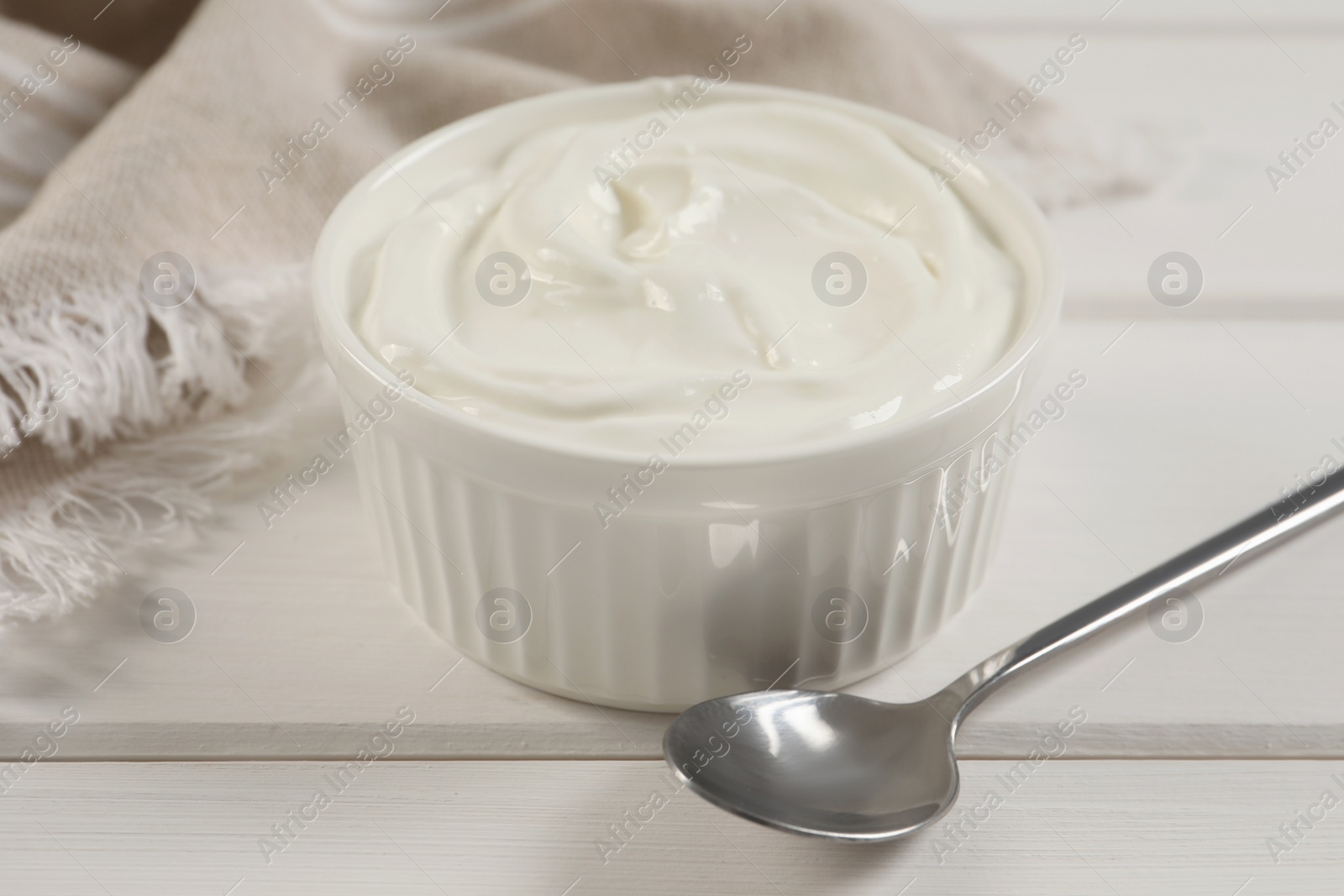 Photo of Bowl of fresh yogurt on white wooden table