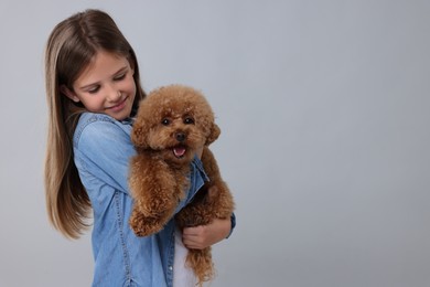 Photo of Little child with cute puppy on light grey background, space for text. Lovely pet