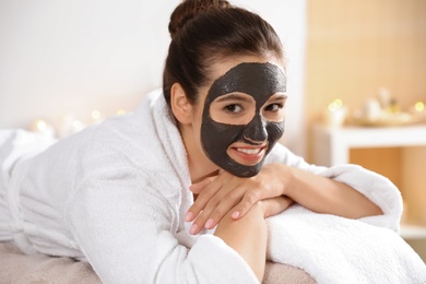 Photo of Beautiful woman with black mask on face relaxing in spa salon