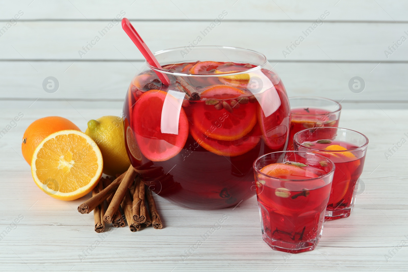 Photo of Aromatic punch drink and ingredients on white wooden table