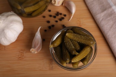 Photo of Tasty pickled cucumbers in glass bowl on wooden table, above view