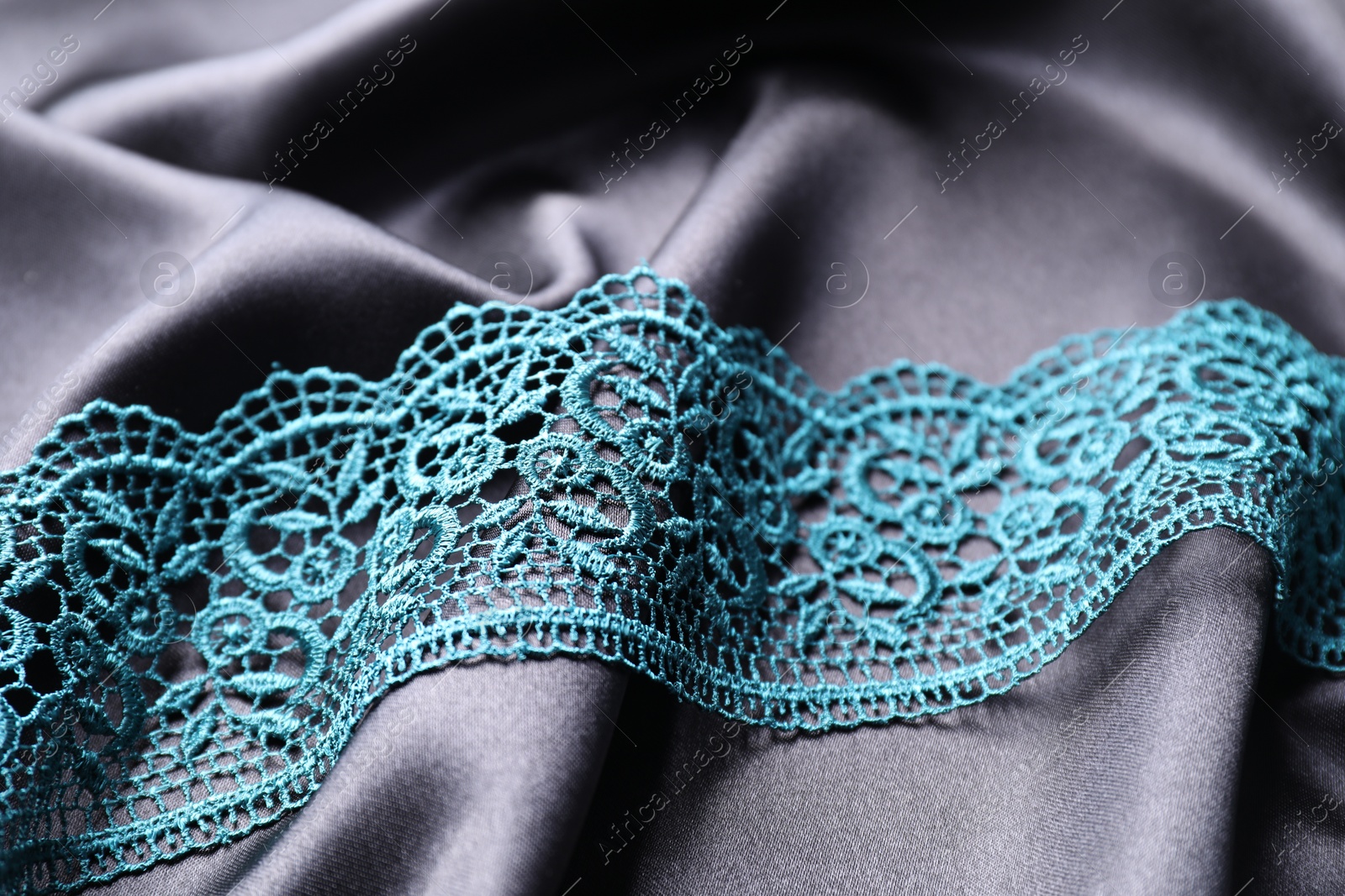 Photo of Beautiful green lace on black fabric, closeup