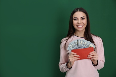 Photo of Young woman with money in wallet on color background. Space for text