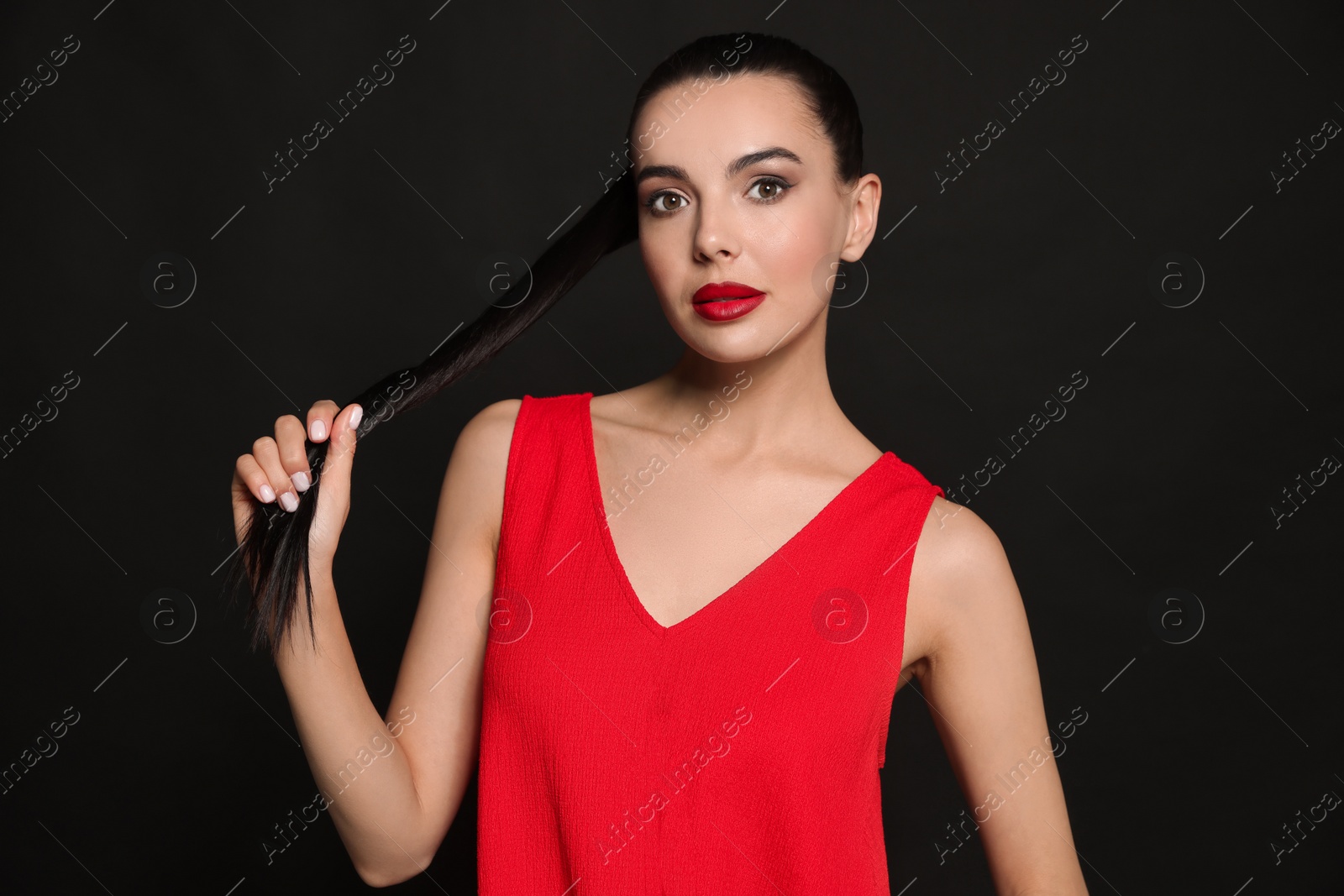 Photo of Portrait of young woman wearing beautiful red lipstick on black background