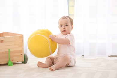 Cute baby playing with ball indoors