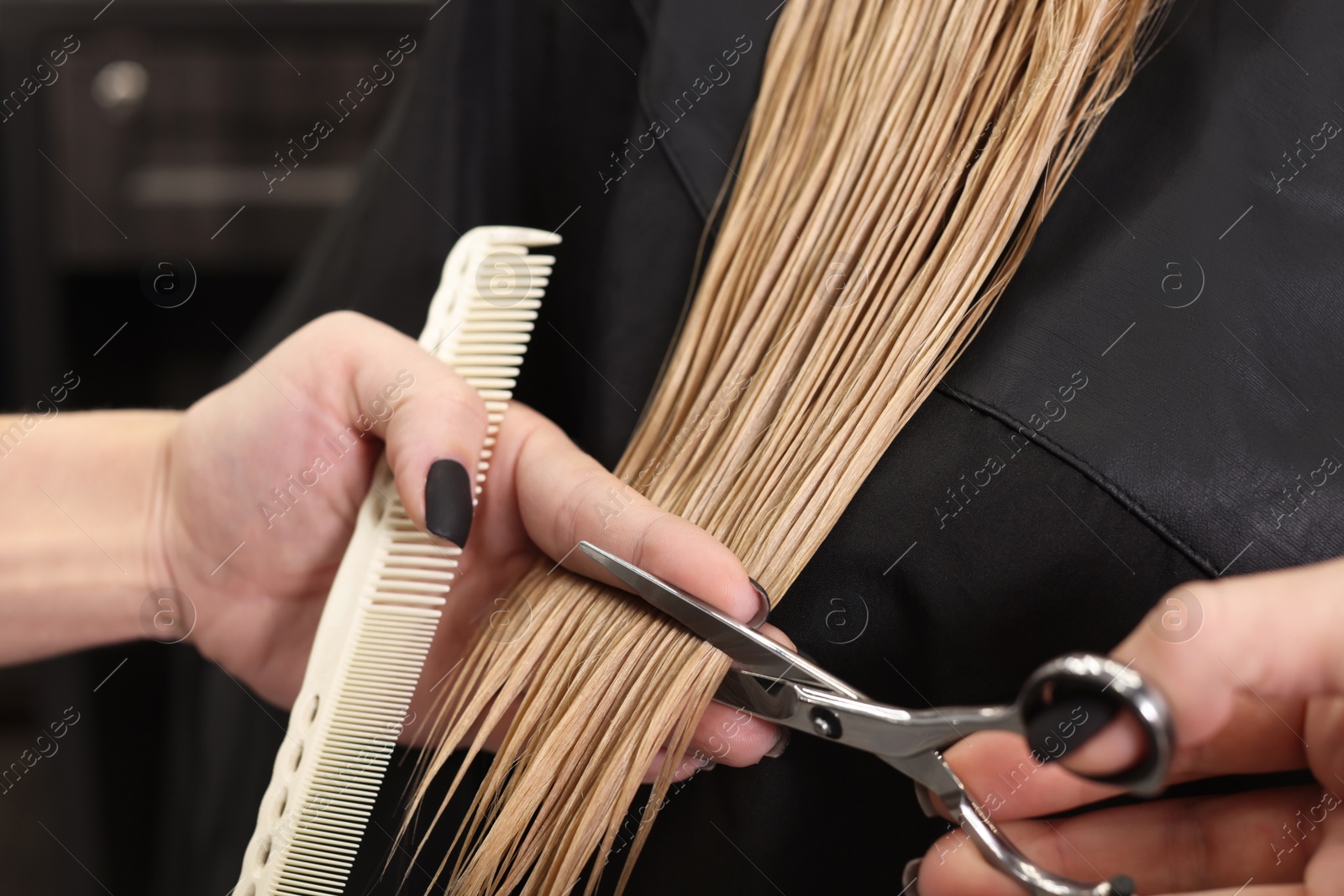 Photo of Professional hairdresser cutting woman's hair in salon, closeup