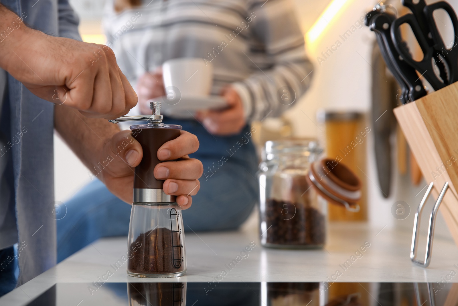 Photo of Couple together in kitchen. Man using manual coffee grinder, closeup