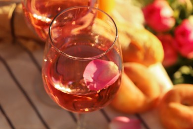 Photo of Glassdelicious rose wine with petals and peaches outside, closeup