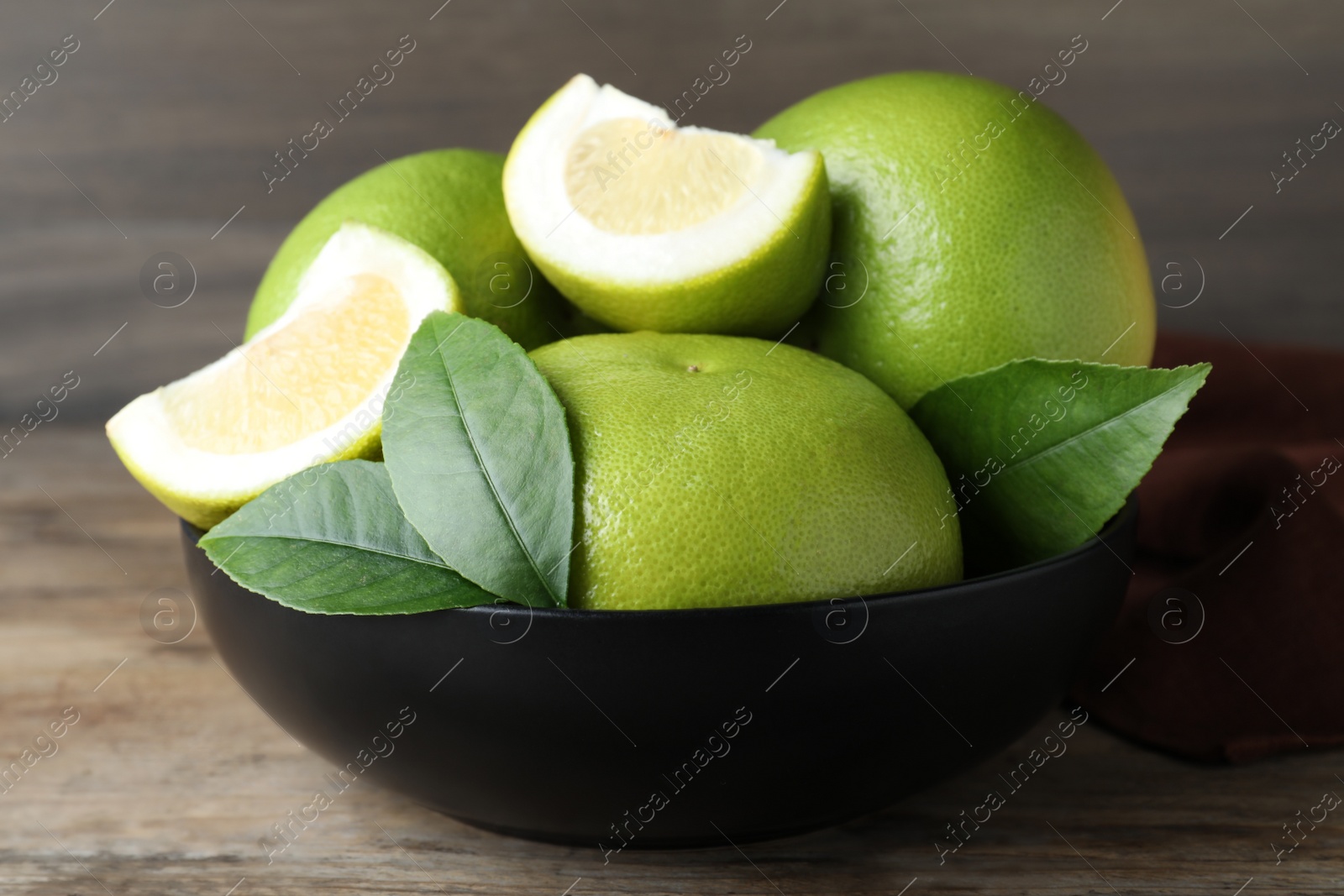 Photo of Fresh ripe sweetie fruits in bowl on wooden table