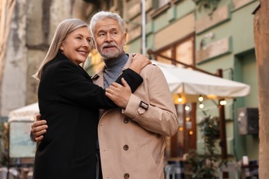 Photo of Affectionate senior couple dancing together on city street. Space for text