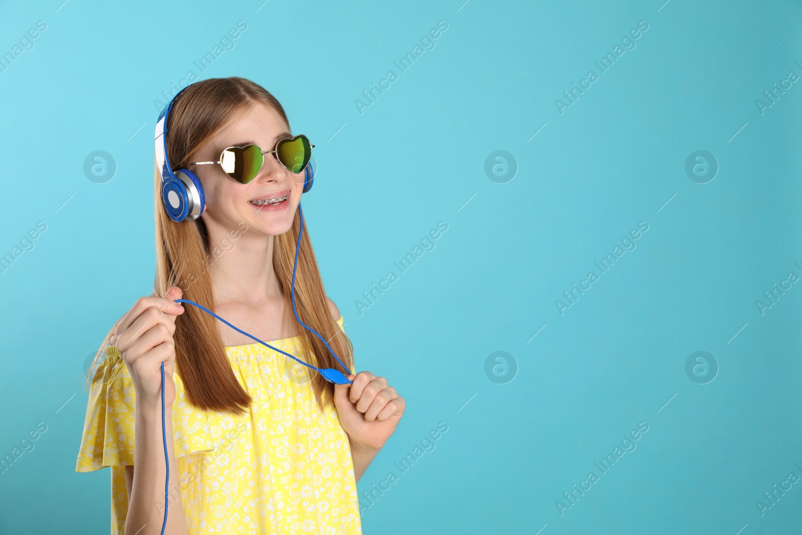 Photo of Teenage girl enjoying music in headphones on color background. Space for text