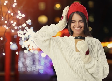 Image of Happy beautiful woman with paper cup of mulled wine at Christmas fair