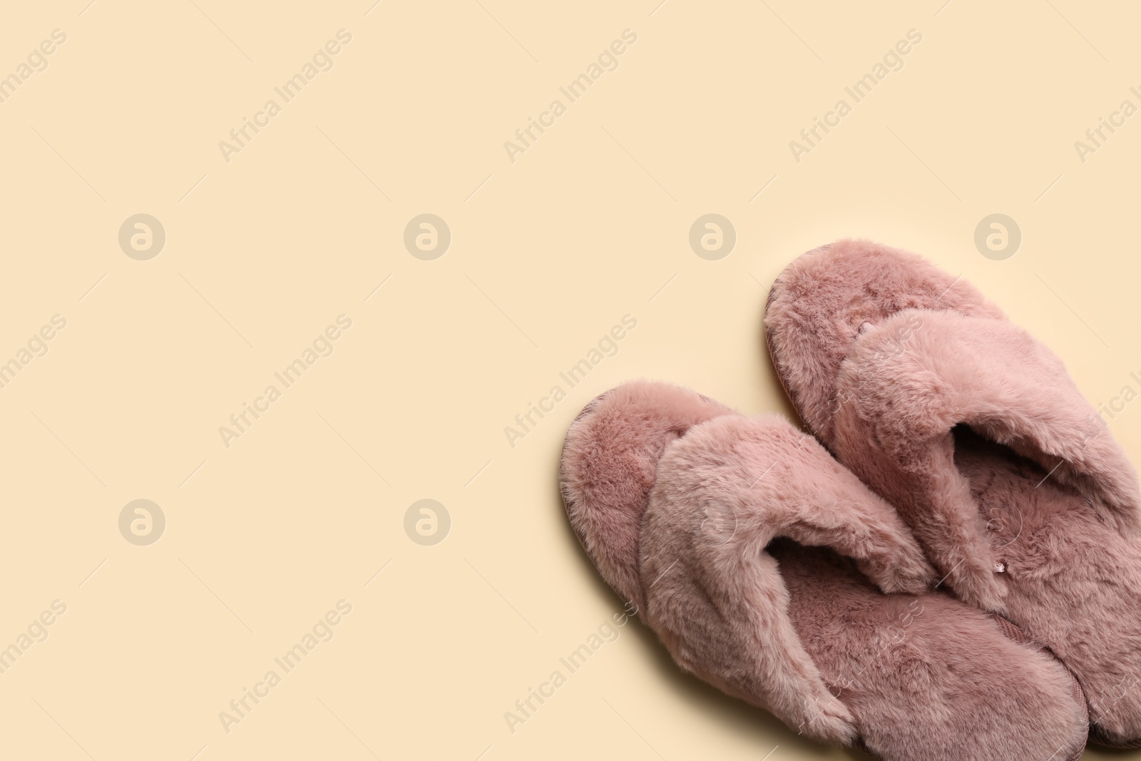 Photo of Pair of stylish soft slippers on beige background, flat lay. Space for text