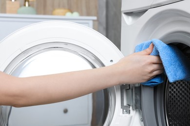 Photo of Woman cleaning washing machine with rag indoors, closeup