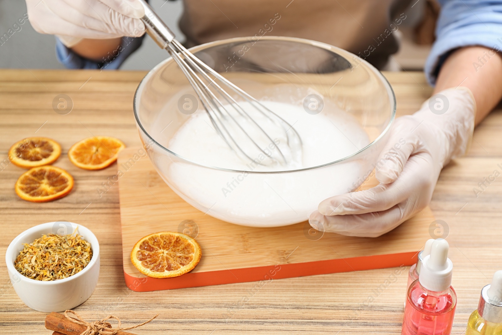 Photo of Woman making natural handmade soap at wooden table, closeup