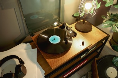 Photo of Stylish turntable with vinyl record on table indoors, above view