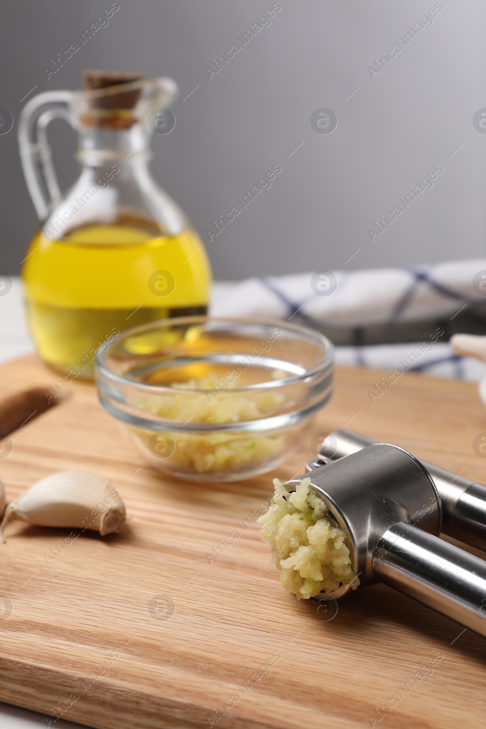 Photo of One metal press and garlic on table, closeup