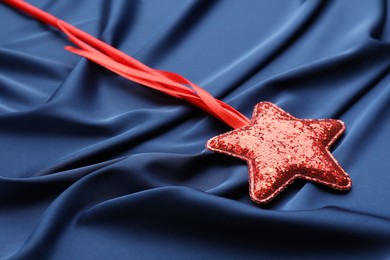 Photo of Beautiful red magic wand on blue fabric