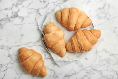 Tasty croissants on marble background, top view